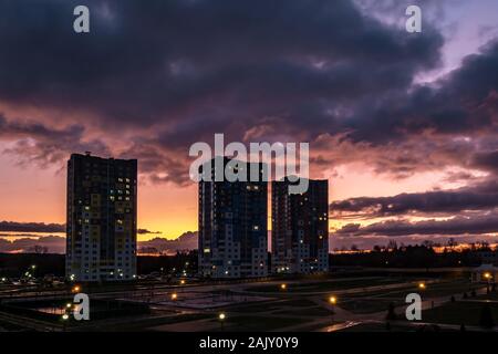 evening fluffy curly rolling clouds of awesome sunset before storm against the background of multi-storey apartment buildings Stock Photo