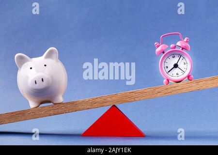 Alarm clock and piggy bank balancing Stock Photo