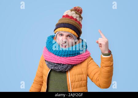 Strict mature man in winter scarf and hat showing index fingers up, warning you Stock Photo