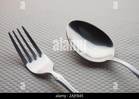 modern silver stainless steel fork and spoon on a table with a white tablecloth. Stock Photo