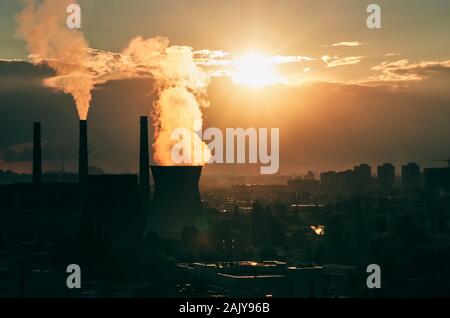 Industrial cityscape of Kyiv, Ukraine. Steam from cooling tower of a coal power plant and smoke from chimneys. Sunset Stock Photo