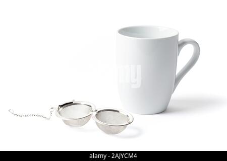 Open and empty metallic tea strainer infuser with a cup isolated on white background. Stock Photo