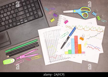 Lap top, statistics plans and office supplies on grey background Stock Photo