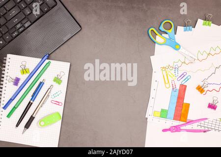 Lap top, statistics plans and office supplies on grey background Stock Photo