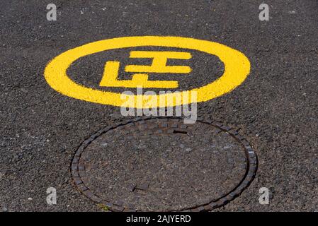 South Africa. December 2019. A freshly painted fire hydrant yellow sign alongside a manhole cover. Stock Photo