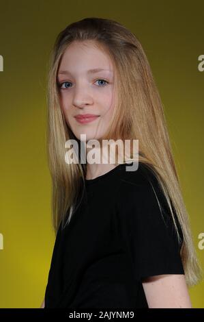 pretty blonde haired Caucasian teenage girl in a black t-shirt isolated on a bright graduated background Stock Photo