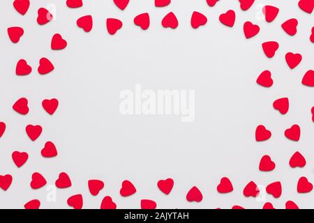 Stock photo of wooden, red and small hearts on a white background. Hearts are spread to frame a text Stock Photo