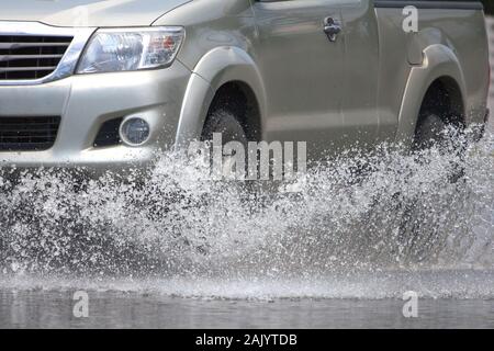 Car splashes through a large puddle on a flooded street Stock Photo