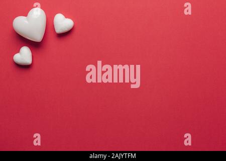 Stock photo of big and small white hearts on a red background. Hearts on the left corner with space for text Stock Photo