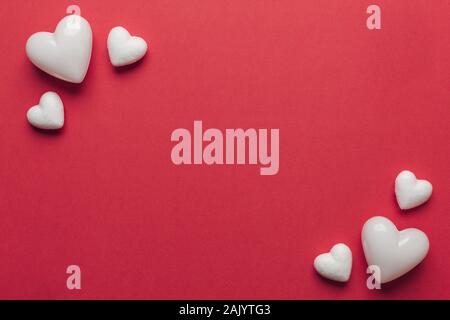 Stock photo of big and small white hearts on a red background. Hearts in the corners with a space for text Stock Photo