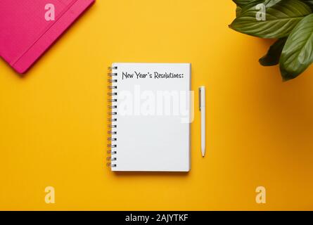 Stock photo of new year notebook with list of resolutions and objects on yellow background Stock Photo