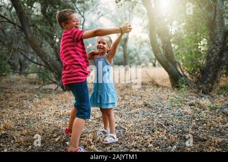 Two kids playing and dancing in the forest Stock Photo