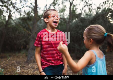 Two kids playing and dancing in the forest Stock Photo
