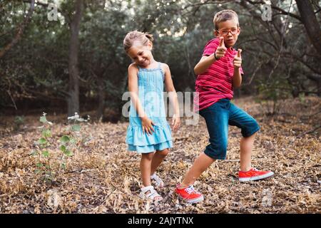 Two kids playing and dancing in the forest Stock Photo