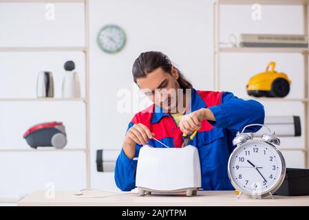 The young male contractor repairing toaster at workshop Stock Photo