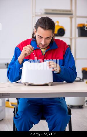 The young male contractor repairing toaster at workshop Stock Photo