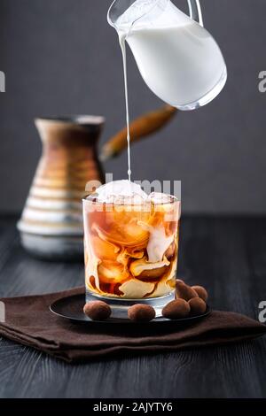 Pouring cream in iced coffee Stock Photo