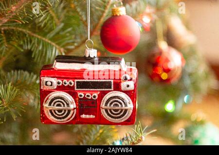 A christmas ornament in the shape of a radio or boom box hanging on the Christmas tree. Texture added. Stock Photo