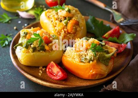 Vegetarian dish. Peppers stuffed with quinoa, shrimp  and vegetables on dark stone table. Stock Photo