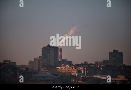 Smoking from industrial chimneys of heating plant emits smoke, smog, pollutants enter atmosphere. Harmful emissions, exhaust gases into air. Heating. Stock Photo