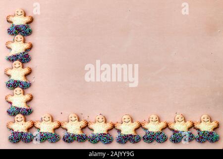 Symbol of Merry Christmas and Happy New Year:  Set of smiling gingerbread man. Sweet holiday cookies isolated on brown Stock Photo