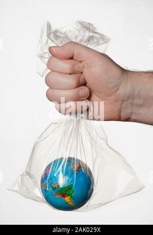 A human hand holding the Earth in a transparent plastic bag. Stock Photo