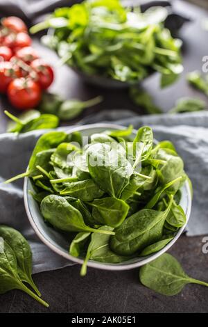 Fresh baby spinach in bowl on dark kitchen table Stock Photo