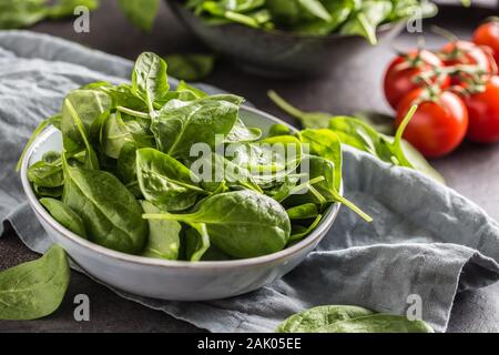 Fresh baby spinach in bowl on dark kitchen table Stock Photo