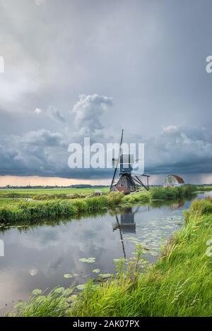 Thunderstorm over a classic dutch landscape with canal and windmill Stock Photo