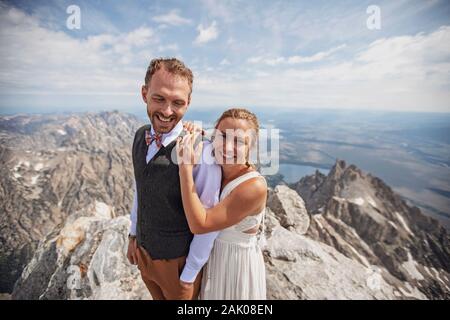 Newlyweds holds each other close after getting married on a mountain Stock Photo