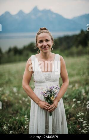 Bride holding wildflower bouquet in a field of flowers, Wyoming Stock Photo