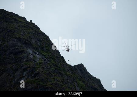 August 21, 2019: Norwegian Sea King rescue helicopter hoisting injured hiker from summit of Reinebringen mountain peak, One of Norway's most popular h Stock Photo