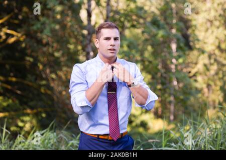 Young man outside in Pacific Northwest adjusts his tie. Stock Photo