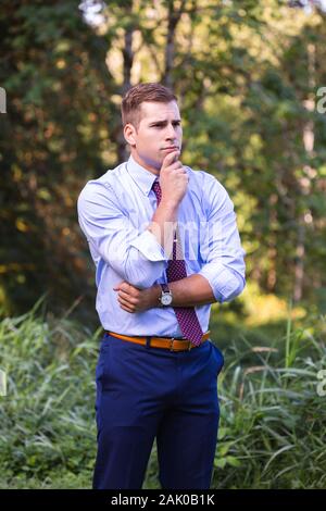 Young man outside with hand on chin deep in thought. Stock Photo