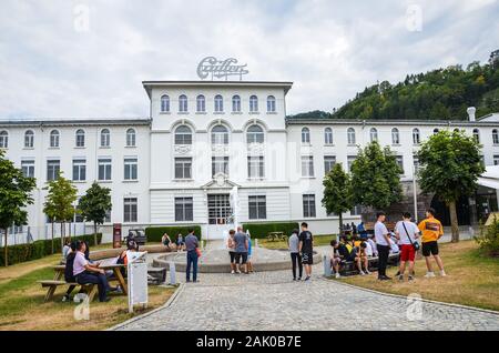 Broc, Switzerland - July 27, 2019: Visitors waiting in front of the building of the famous Cailler chocolate factory. People in the courtyard of the areal. Tour and museum. Swiss chocolate. Stock Photo