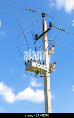 Distribution of electricity.Transformer of high power station on the pillar against the blue sky. Electrical energy Stock Photo
