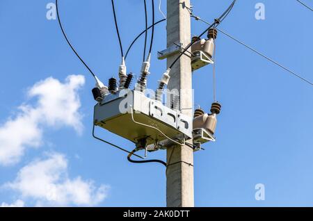 Distribution of electricity.Transformer of high power station on the pillar against the blue sky. Electrical energy Stock Photo