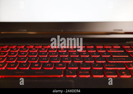 red glowing back lit keyboard of a gaming laptop with white mockup screen. Stock Photo