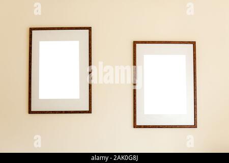 Minimalist empty wooden frames hanging out on a background of a beige wall. Stock Photo