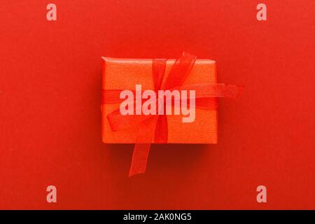 Red present gift with red ribbon on red background. Valentines day love, romance, heart Concept. Valentines day minimal composition top view, flat lay Stock Photo
