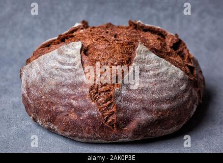 Artisan loaf of traditional Homemade Pumpernickel sourdough Boule bread with crust on a wooden board Stock Photo