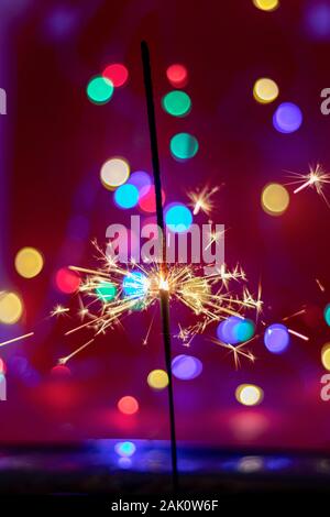 Glittering burning sparkler on red and color bukeh  background Stock Photo