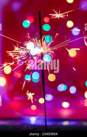 Glittering burning sparkler on red and color bukeh  background Stock Photo