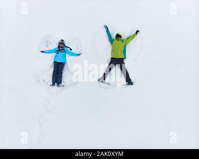 couple having fun making snow angel Stock Photo