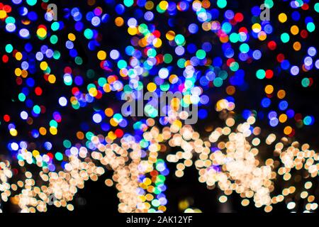 Defocused Christmas lights adorning a tree; Background bokeh of colorful lights; abstract background Stock Photo