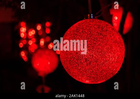 Close up of Christmas red bauble hanging from a branch; dark background; night scene Stock Photo