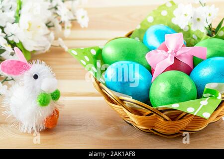 Little Toy Bunny On Wooden Background and  Basket With Decorated Eggs On Wooden Background  - Easter Card. Stock Photo
