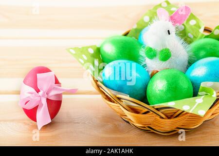 Little Toy Bunny In Basket With Decorated Eggs On Wooden Background - Easter Card. Copy space Stock Photo