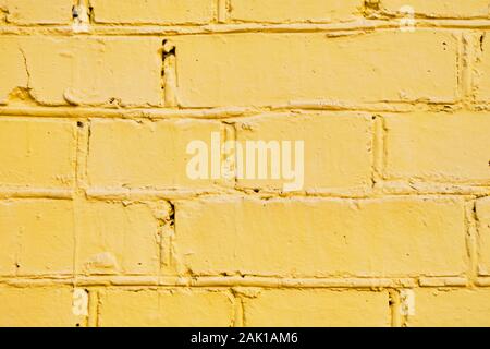 The brick wall is painted yellow. Background. Close up. Stock Photo