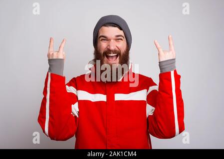 Photo of amazed climber in winter clothes showing rock gesture Stock Photo